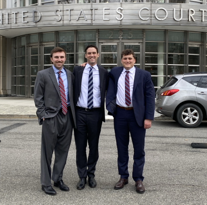 three men in business suits smiling outside courthouse